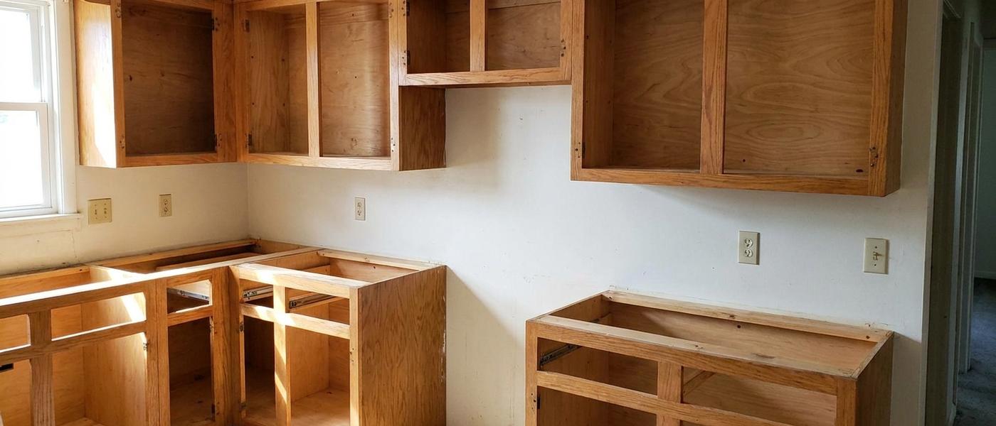 An older kitchen stripped back to bare wooden cabinet boxes and face frames with all doors, drawer fronts and the countertop removed